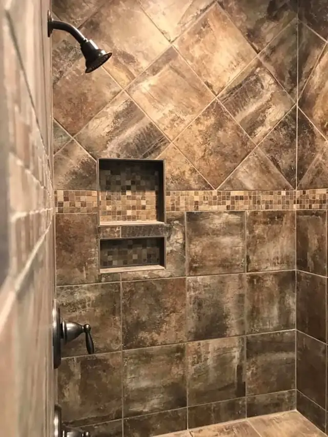 Shower with brown stone-look tile set on the diagonal, a mosaic band and two recessed niches